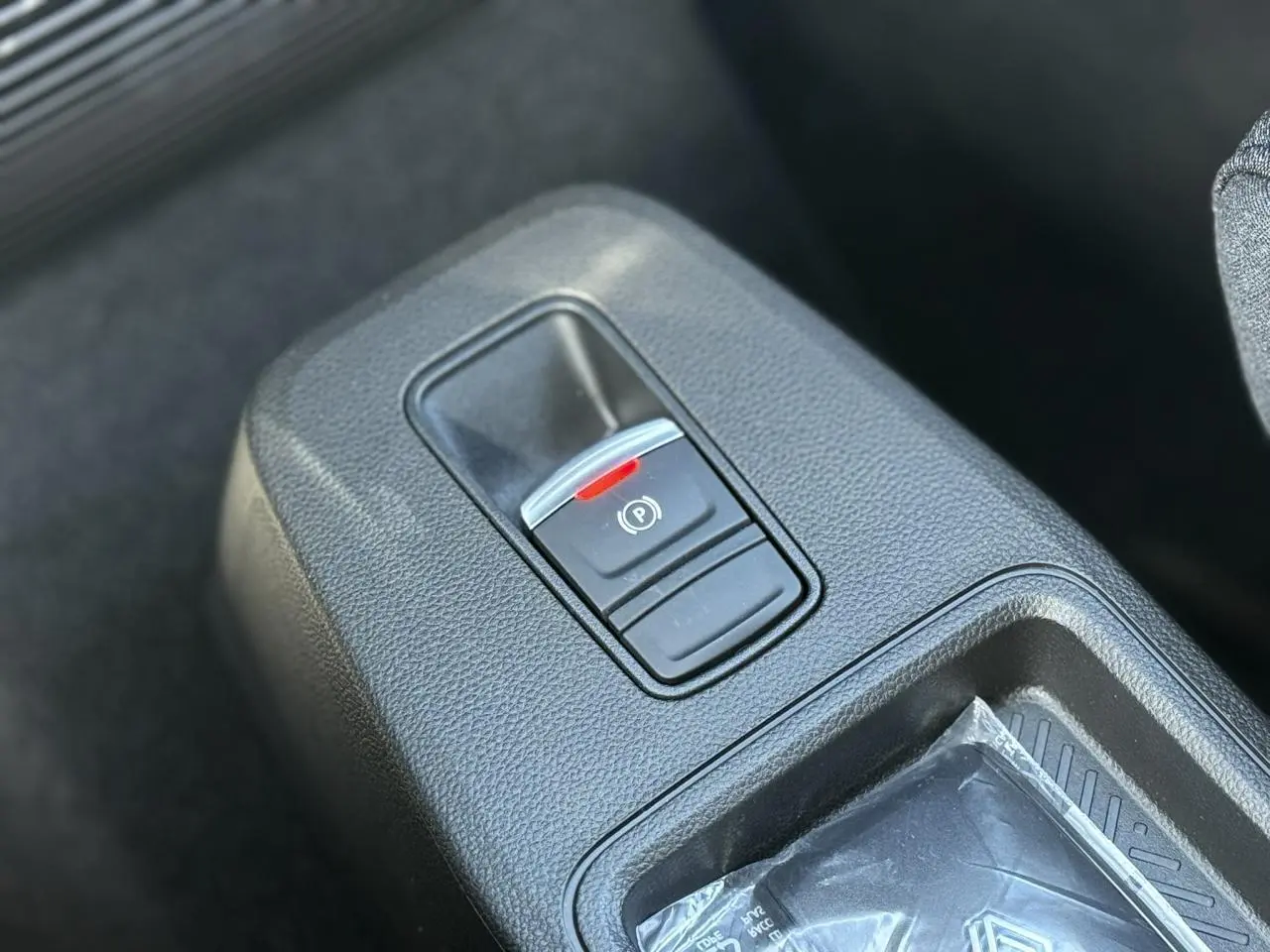 Gros plan sur le frein de parking électrique dans la console centrale d’une Renault R5 E-Tech Electrique blanche.