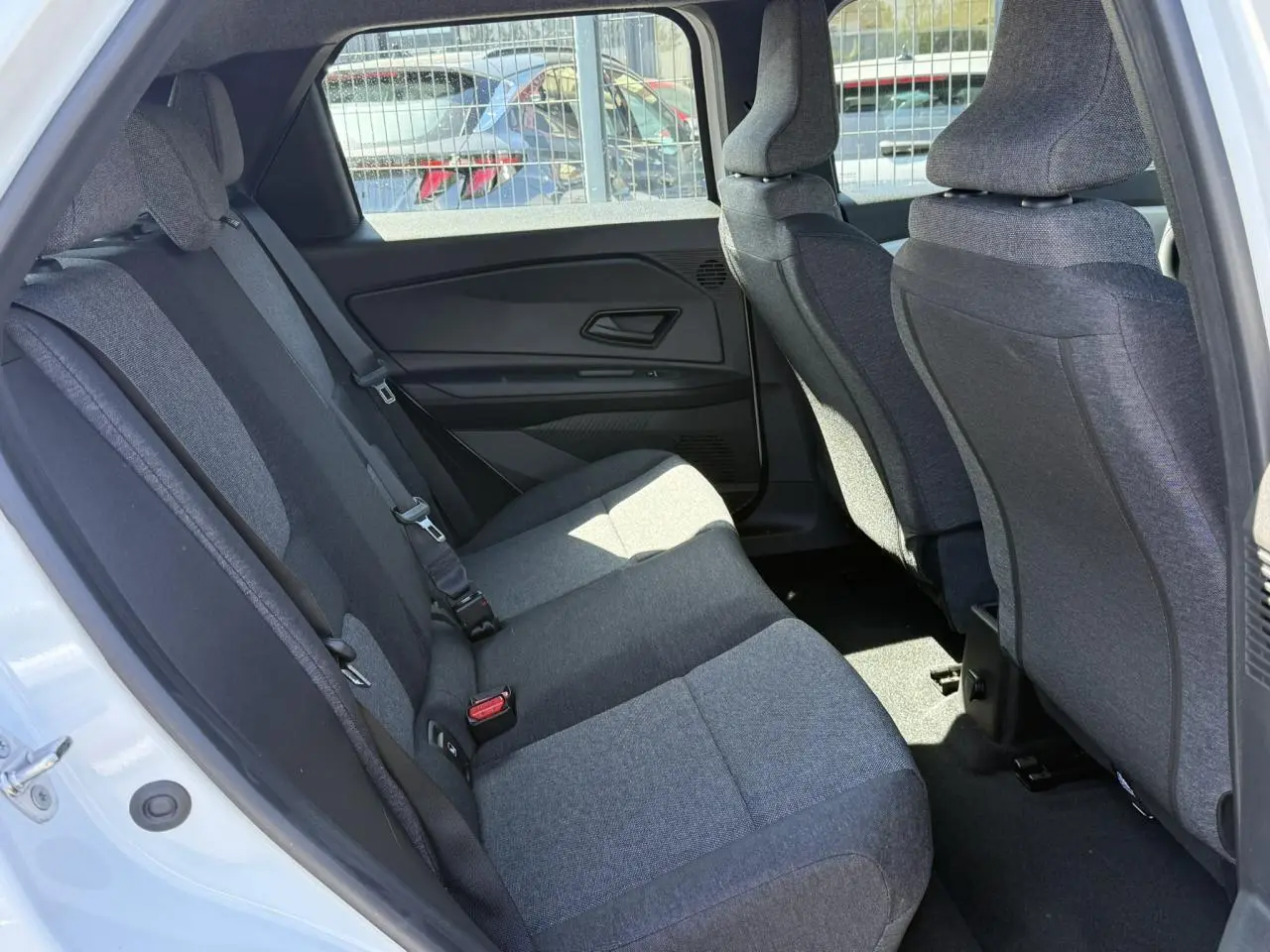 Vue intérieure arrière côté gauche de la Renault R5 E-Tech 2026, sièges tissu gris et portières noires.