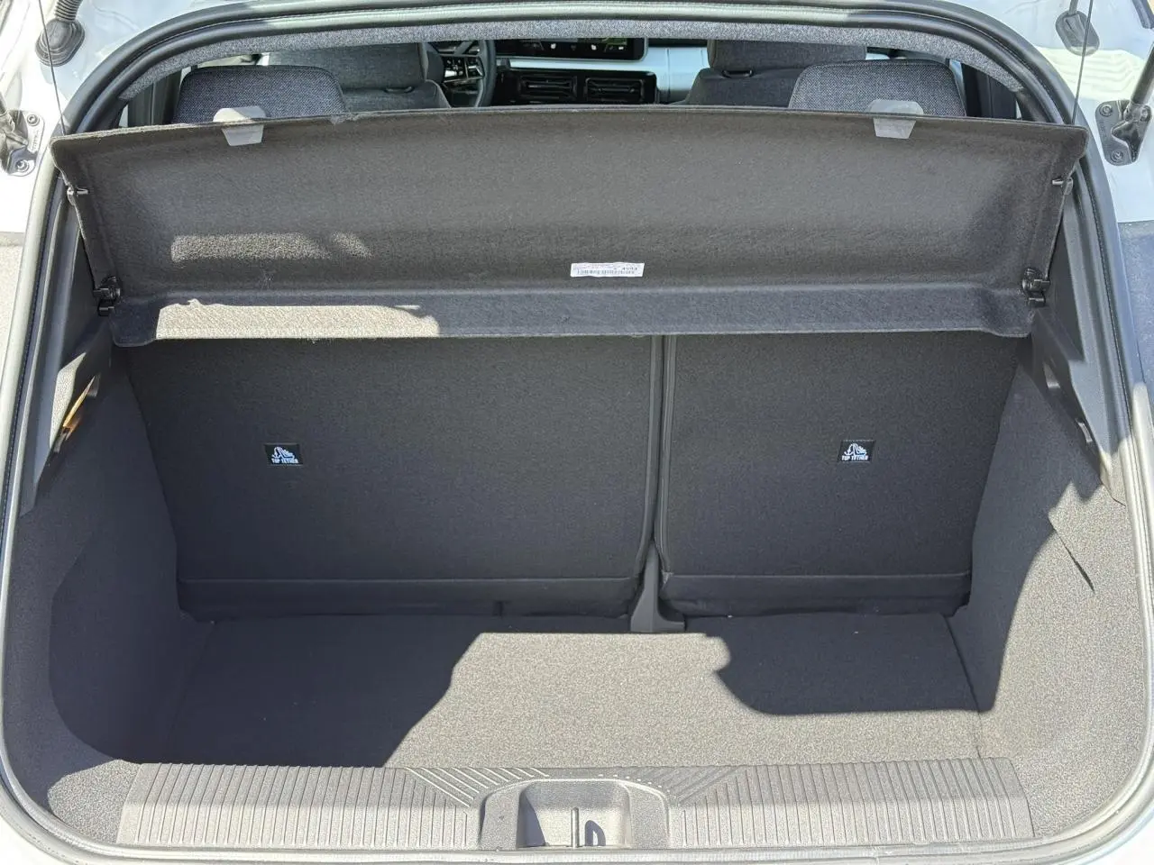 Coffre ouvert vu de l'arrière d'une Renault R5 E-Tech Electrique blanc nacré, intérieur noir et tablette de séparation.