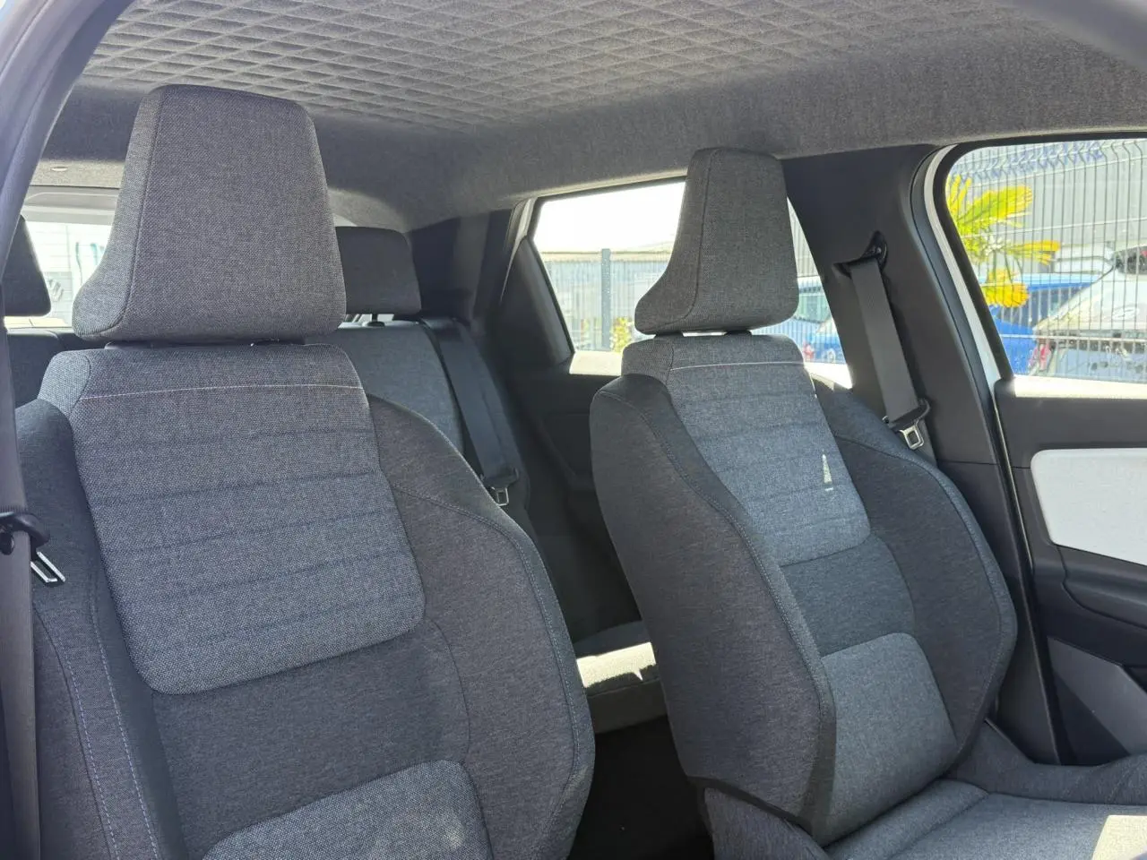 Vue intérieure des sièges avant en textile gris matelassé avec surpiqûres bleu, blanc, rouge dans une Renault R5 E-Tech blanc nacré.