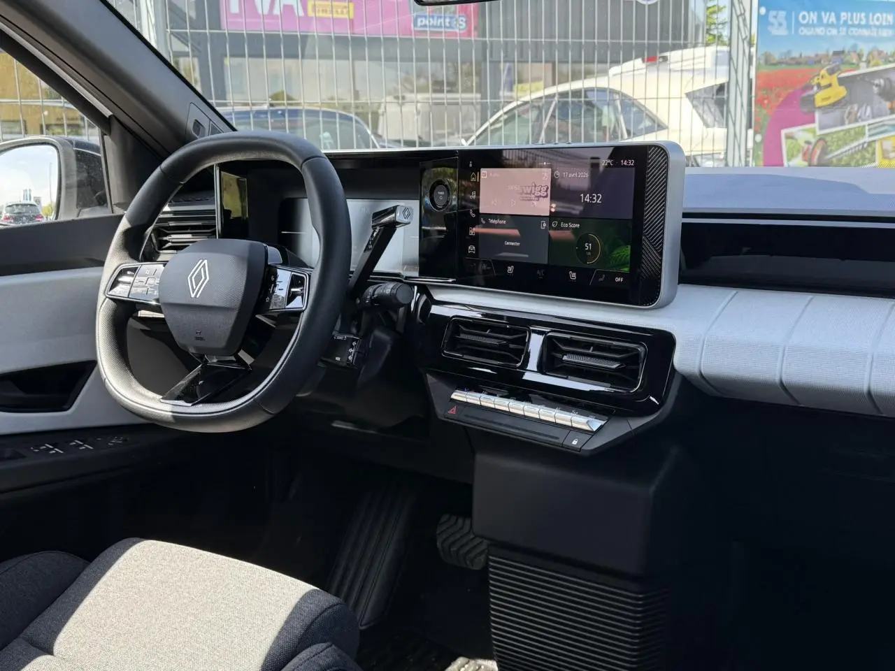 Vue intérieure côté conducteur de la Renault R5 E-Tech 2026, tableau de bord blanc nacré avec écran tactile central et volant multifonction.