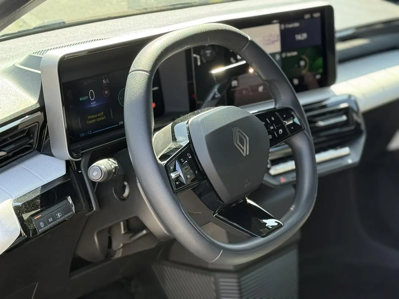 Vue intérieure centrée sur le volant multifonction noir et le tableau de bord numérique de la Renault R5 E-Tech blanc nacré.
