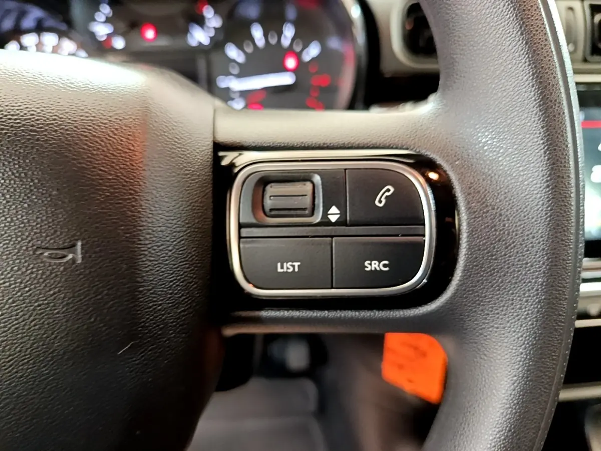 Gros plan sur les commandes gauche du volant noir de la Citroën C3 2021, avec boutons de gestion audio et appels.