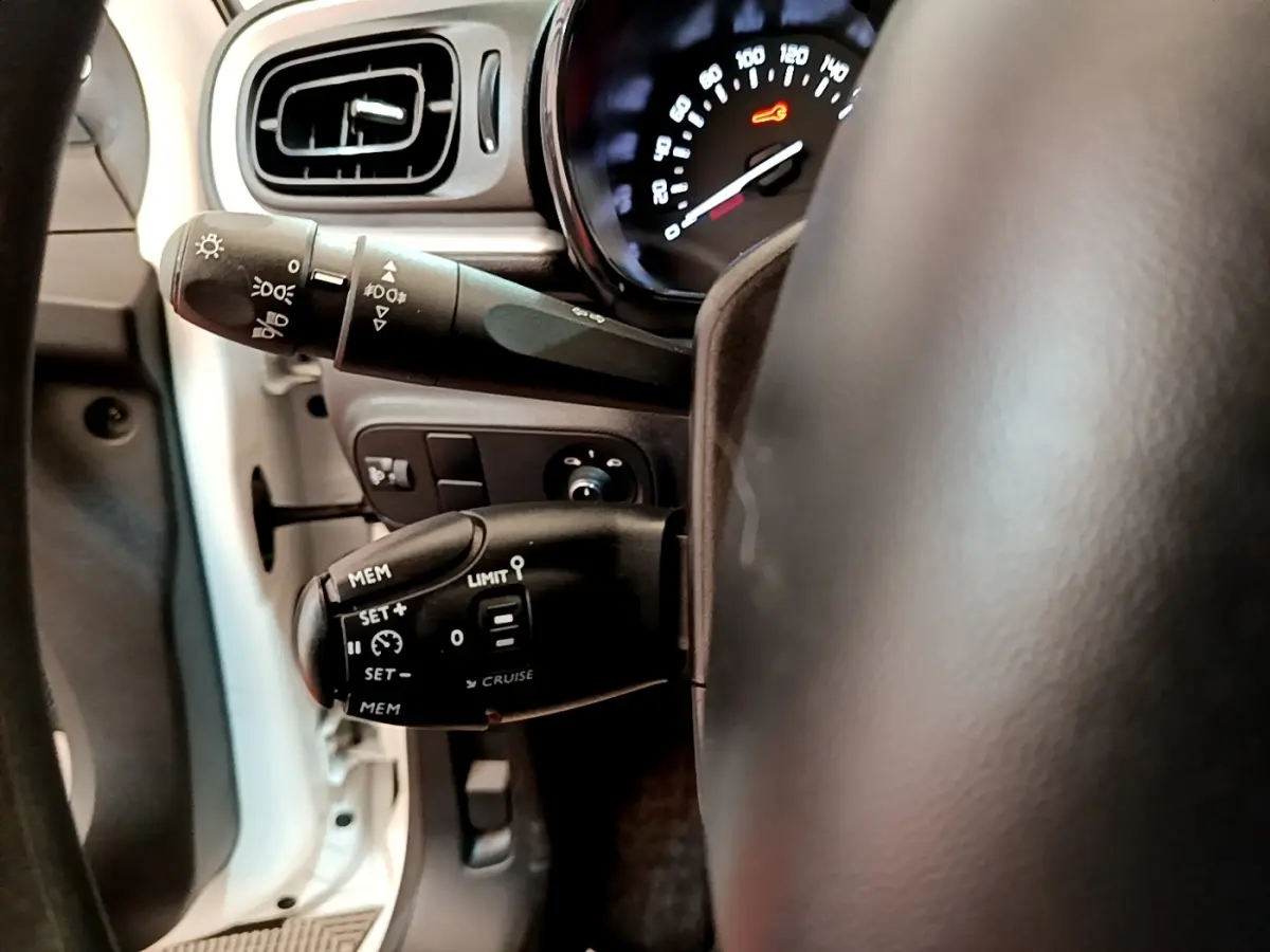 Gros plan sur la commande de régulateur de vitesse et clignotants côté gauche du volant d’une Citroën C3 blanche 2021.