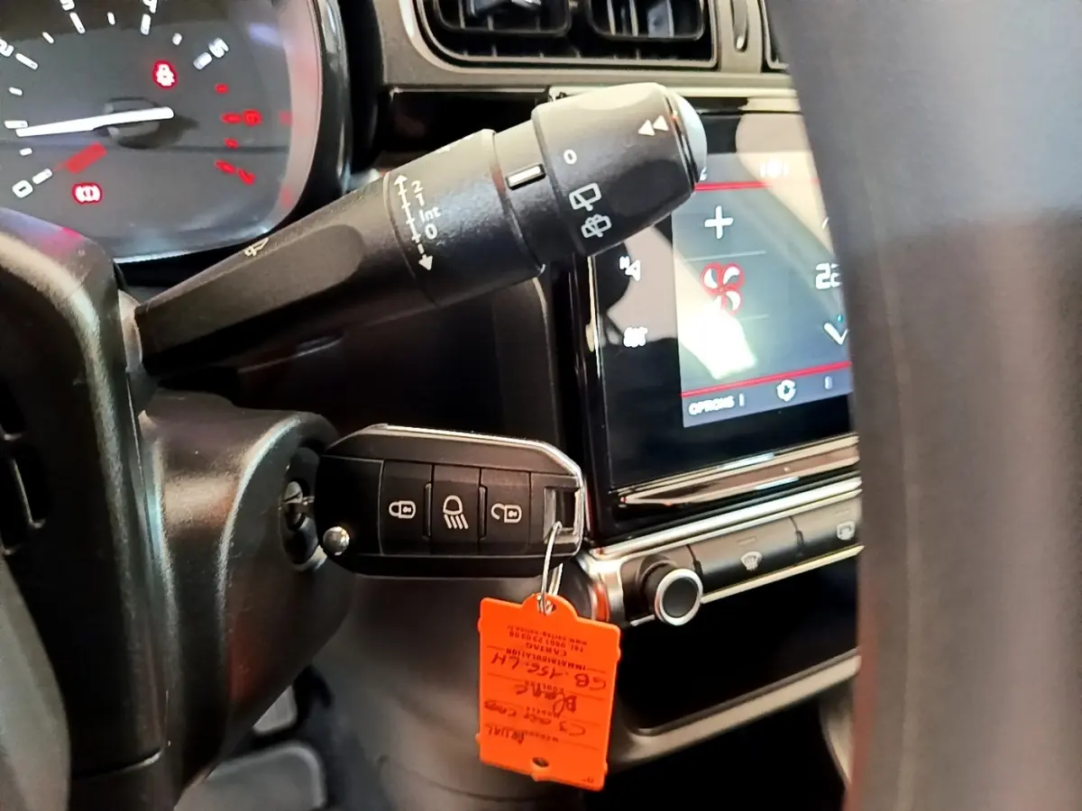 Gros plan intérieur sur le tableau de bord et la clé insérée d'une Citroën C3 blanche, avec écran tactile et commandes visibles.