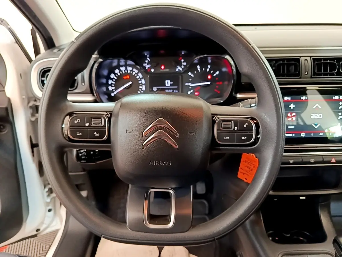 Vue intérieure centrée sur le volant noir d'une Citroën C3 blanche, avec tableau de bord et écran tactile visibles.