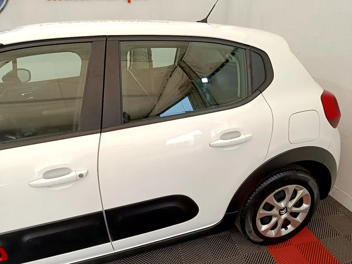 Vue latérale droite d'une Citroën C3 blanche 2021 avec protections noires sur les portières et jantes alliage.