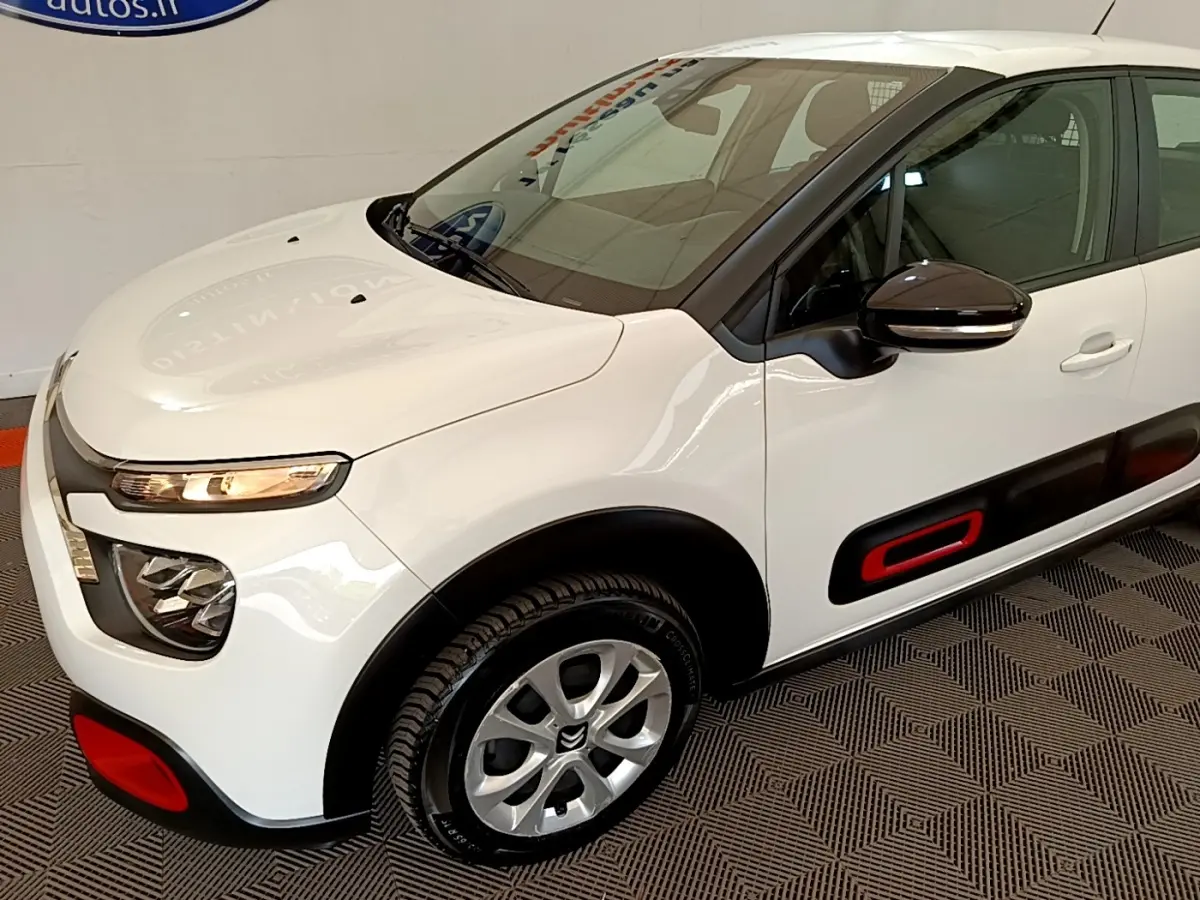 Vue 3/4 avant droite d'une Citroën C3 blanche avec inserts rouges sur les protections latérales et pare-chocs.