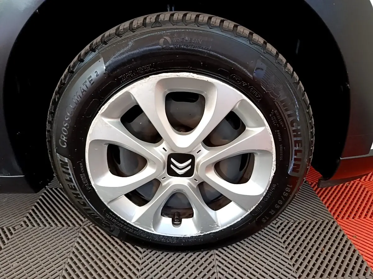 Gros plan sur la roue avant droite d'une Citroën C3 blanche, mettant en valeur la jante en alliage et le pneu Michelin.