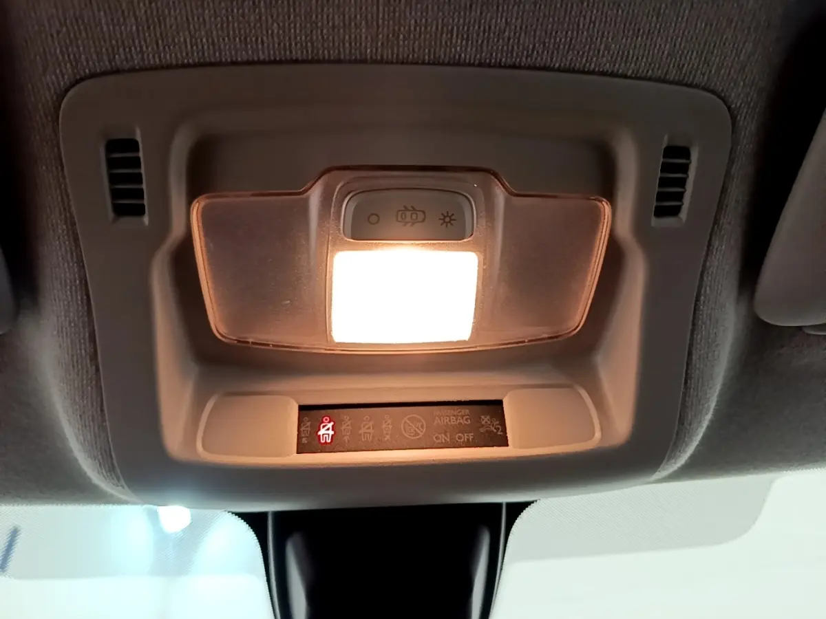Plafonnier intérieur allumé avec témoin de ceinture de sécurité rouge dans une Citroën C3 blanche, vue du plafond avant.