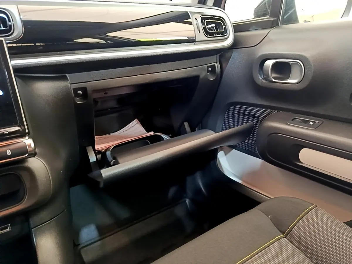 Intérieur de la Citroën C3 blanc, vue côté passager montrant la boîte à gants ouverte et la porte avec haut-parleur intégré.