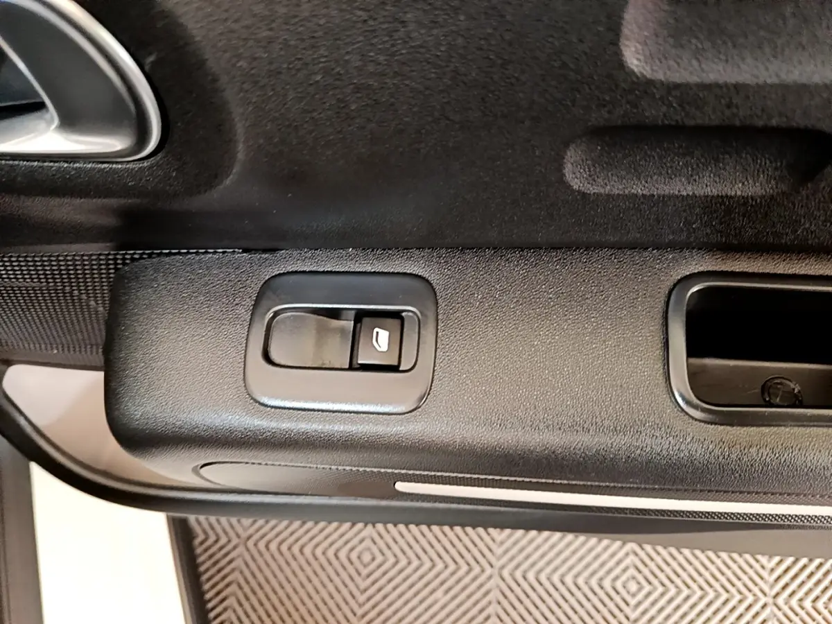 Gros plan sur la commande de lève-vitre côté gauche de la porte intérieure noire d'une Citroën C3 blanche de 2021.
