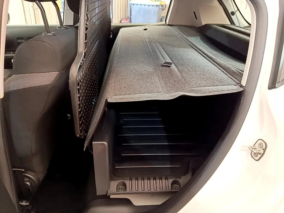 Vue intérieure arrière côté droit du coffre d'une Citroën C3 blanche 2021 avec cache-bagages déployé.