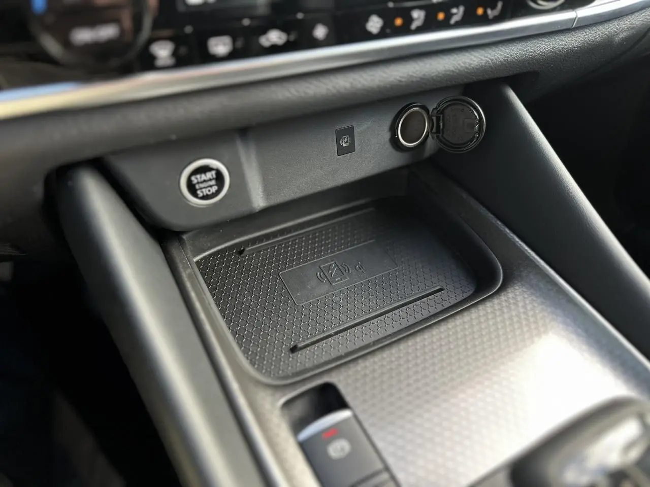 Gros plan sur la console centrale noire du Nissan Qashqai 2025, avec bouton start/stop et chargeur sans fil.