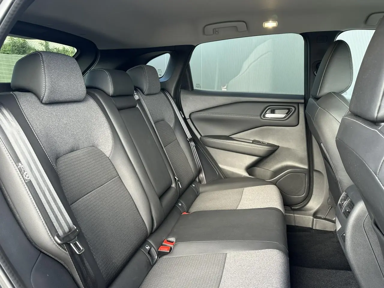 Vue intérieure côté droit des sièges arrière en sellerie mixte noir et tissu gris du Nissan Qashqai 2025.