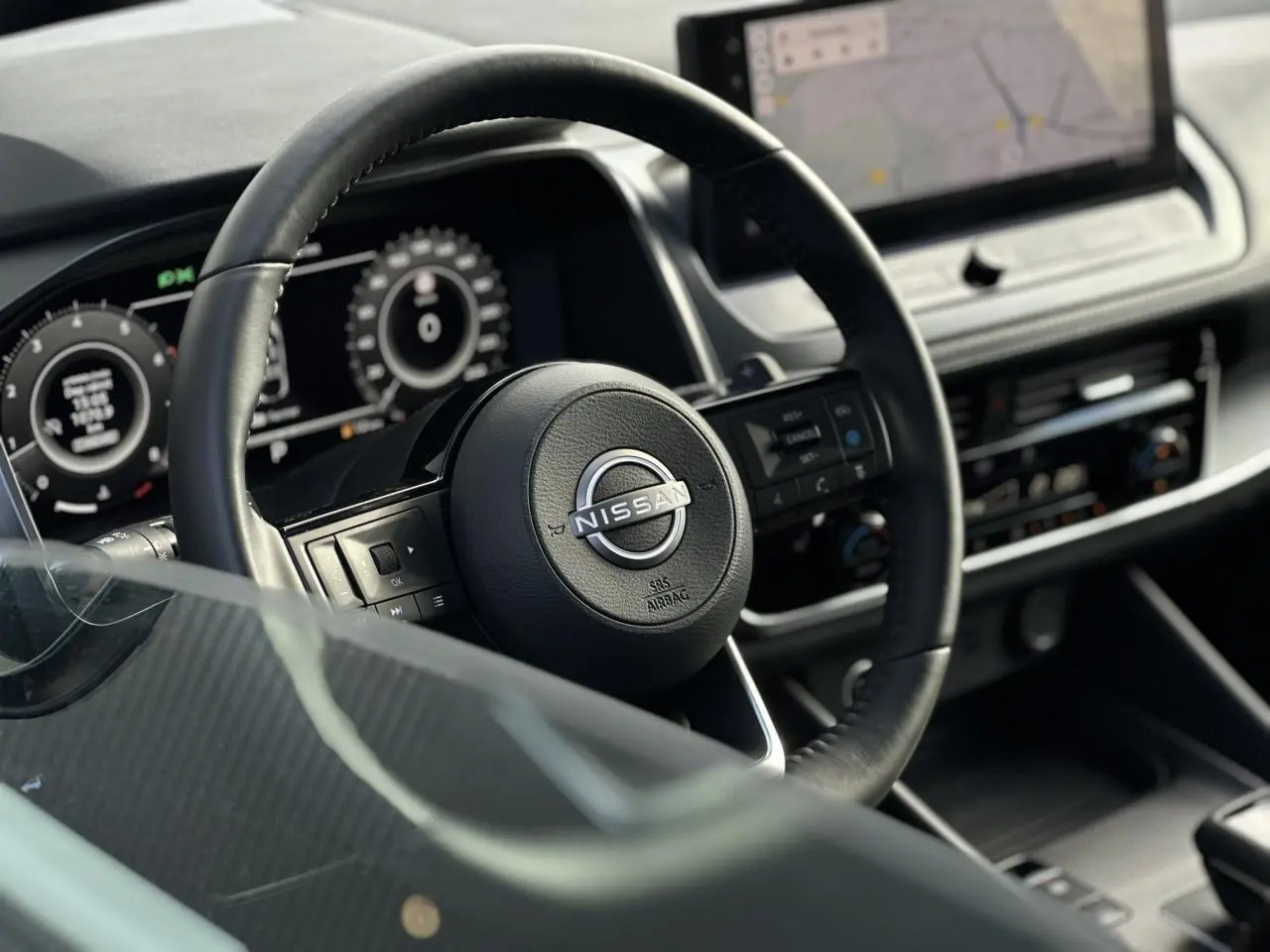 Vue rapprochée du volant cuir noir Nissan Qashqai 2025 avec tableau de bord numérique et écran tactile central.