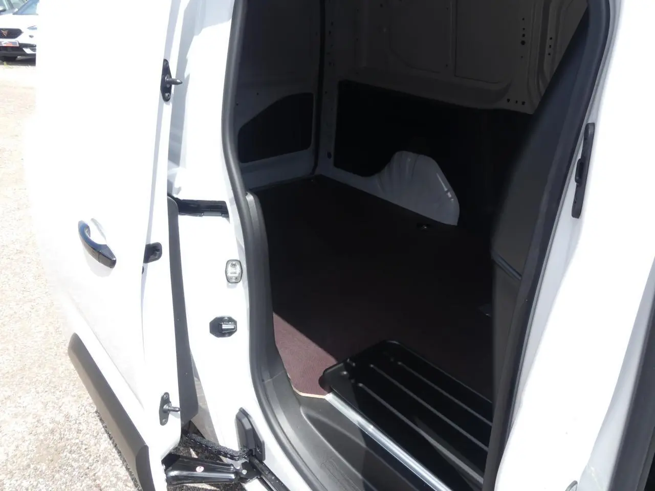 Vue rapprochée de l'ouverture de la porte latérale droite du Peugeot Partner blanc, montrant l'espace de chargement intérieur.