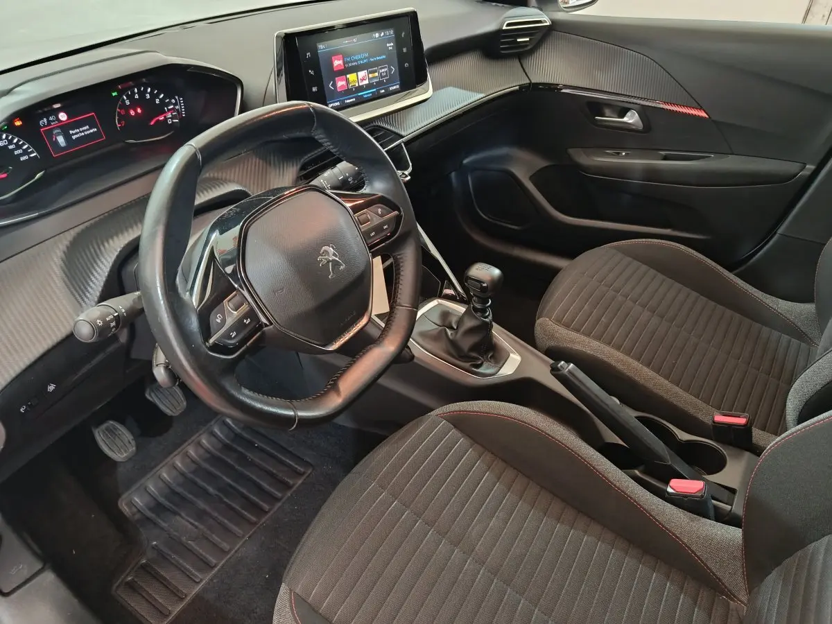 Vue intérieure côté conducteur du Peugeot 208 blanc 2020, volant cuir, tableau de bord numérique et écran tactile central.