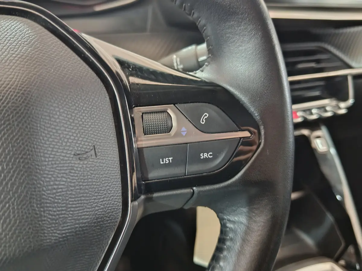 Gros plan sur les commandes du volant cuir noir de la Peugeot 208 PureTech 100 S&S Active Business 2020.