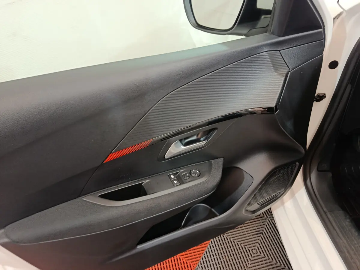 Vue rapprochée de la porte avant gauche blanche d'une Peugeot 208 2020, avec garniture noire et insert rouge.