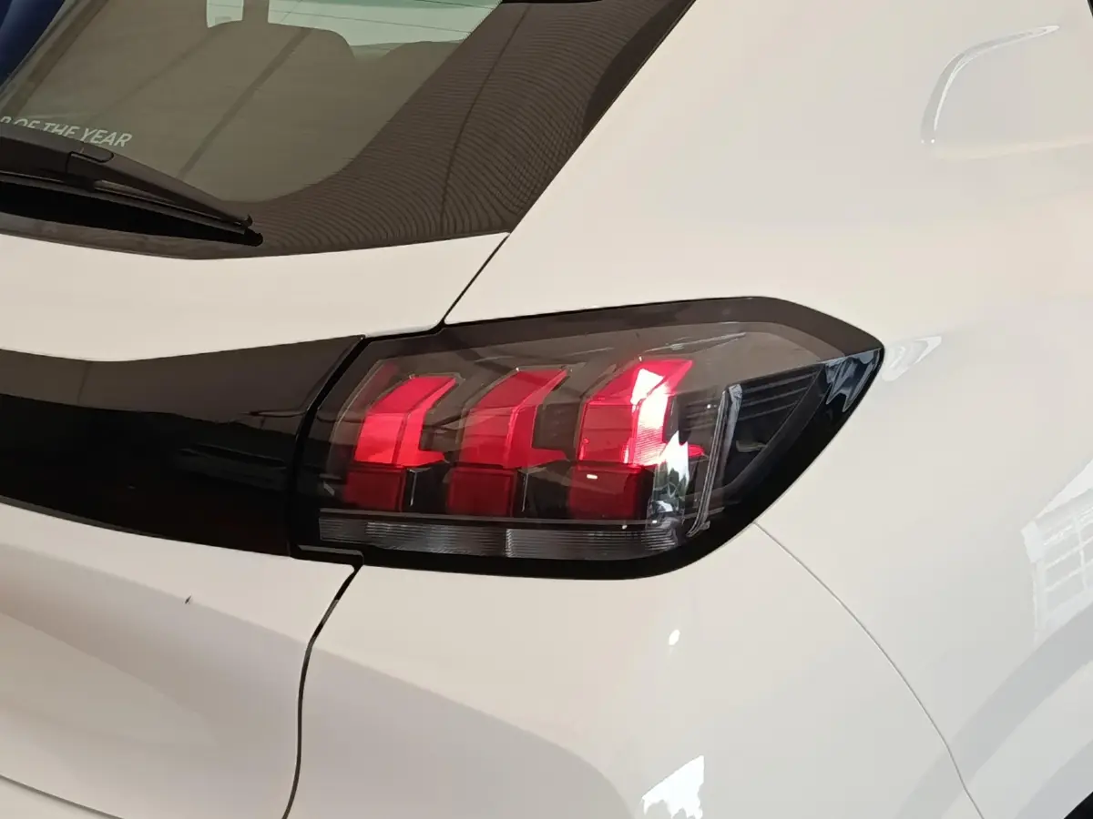 Gros plan sur le feu arrière droit rouge et noir d'une Peugeot 208 blanche vue de l'arrière.