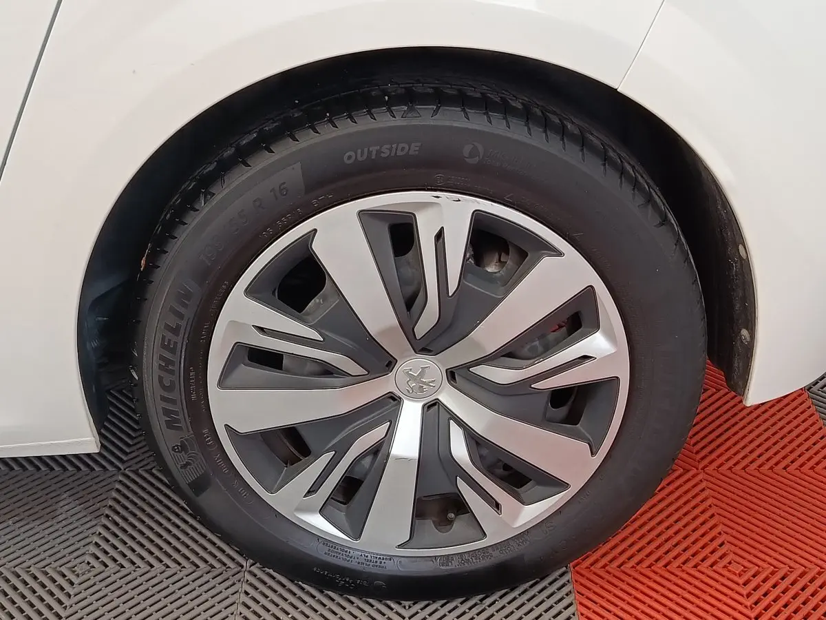 Gros plan sur la roue avant gauche blanche d'une Peugeot 208 PureTech 100 S&S Active Business avec jante en alliage moderne.