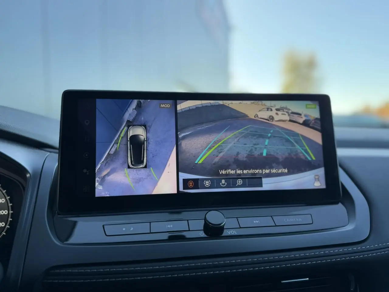 Écran central intérieur montrant la caméra de recul et la vue 360° du Nissan Qashqai blanc nacré 2025.