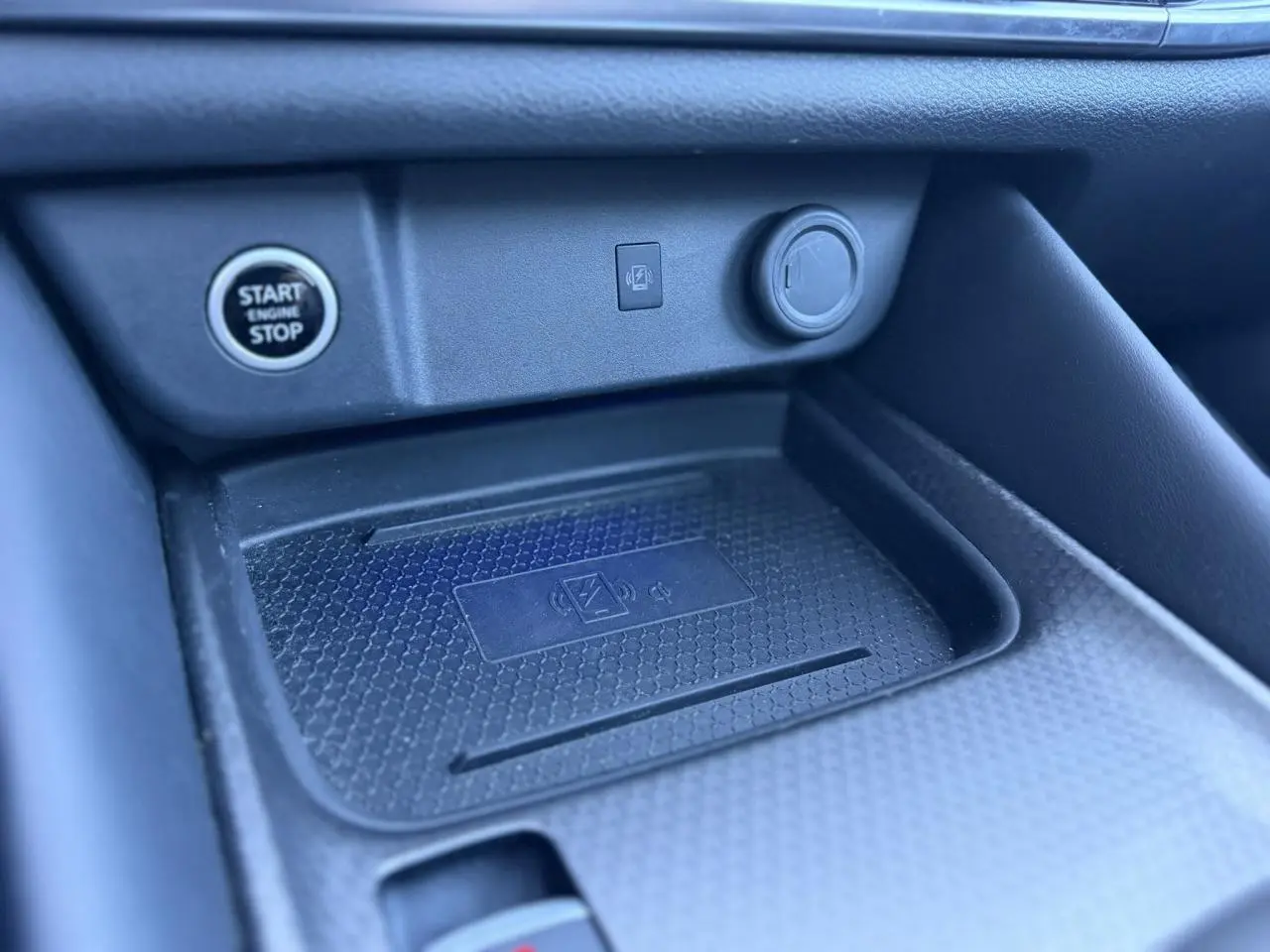 Gros plan sur le chargeur à induction et bouton Start/Stop dans l’habitacle noir du Nissan Qashqai 2025.