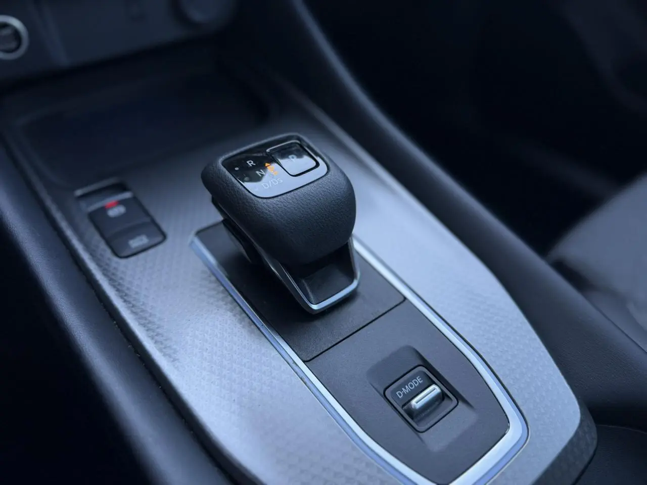 Gros plan sur la console centrale du Nissan Qashqai 2025, avec levier de vitesse automatique et bouton D-MODE.