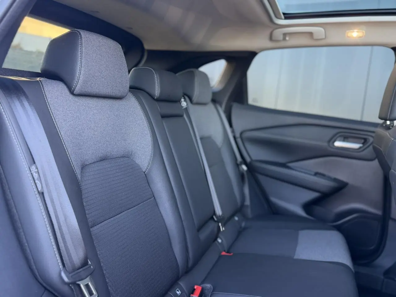 Vue intérieure côté droit des sièges arrière en tissu et TEP noir du Nissan Qashqai 2025 avec ceinture de sécurité visible.