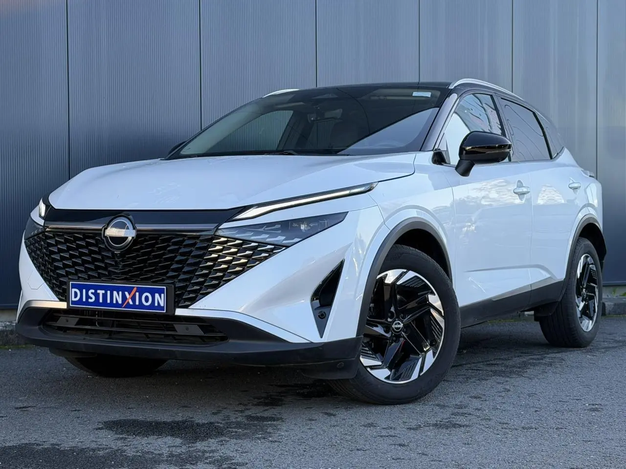 Nissan Qashqai blanc nacré avec toit noir, vue 3/4 avant, calandre noire et jantes alliage bicolores.