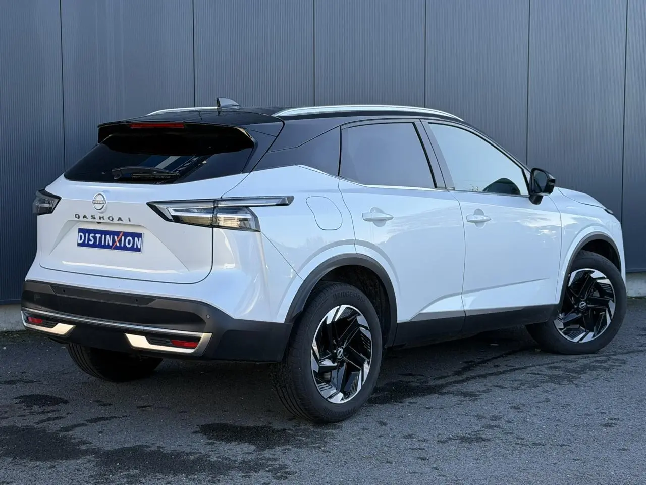 Vue 3/4 arrière droite du Nissan Qashqai blanc nacré avec toit noir et jantes alliage noires.