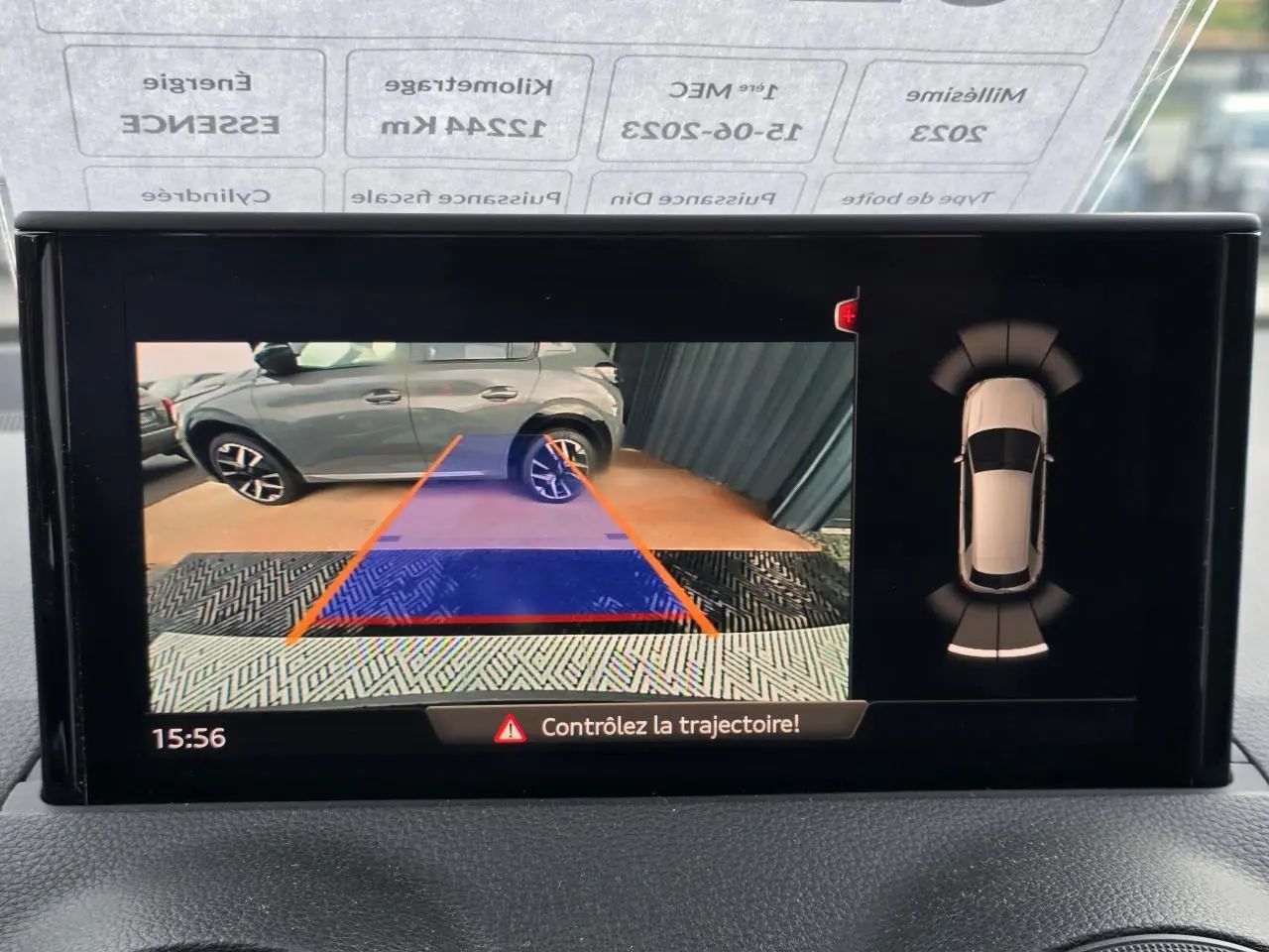 Vue écran caméra de recul montrant un Audi Q2 noir mythic garé côté droit avec lignes de guidage orange.