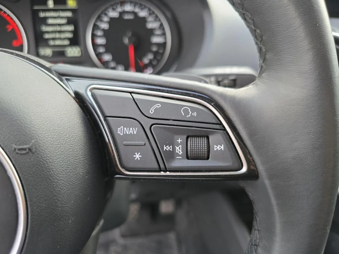 Gros plan sur les commandes du volant cuir noir de l'Audi Q2 35 TFSI 150 Design S-Line 2023.