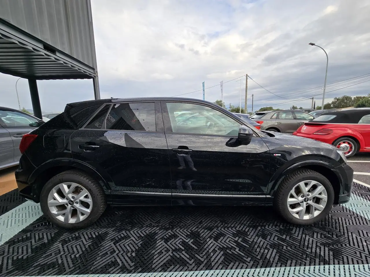 Audi Q2 noir mythic vue de profil côté gauche, avec jantes aluminium 5 branches doubles et vitres arrière surteintées.