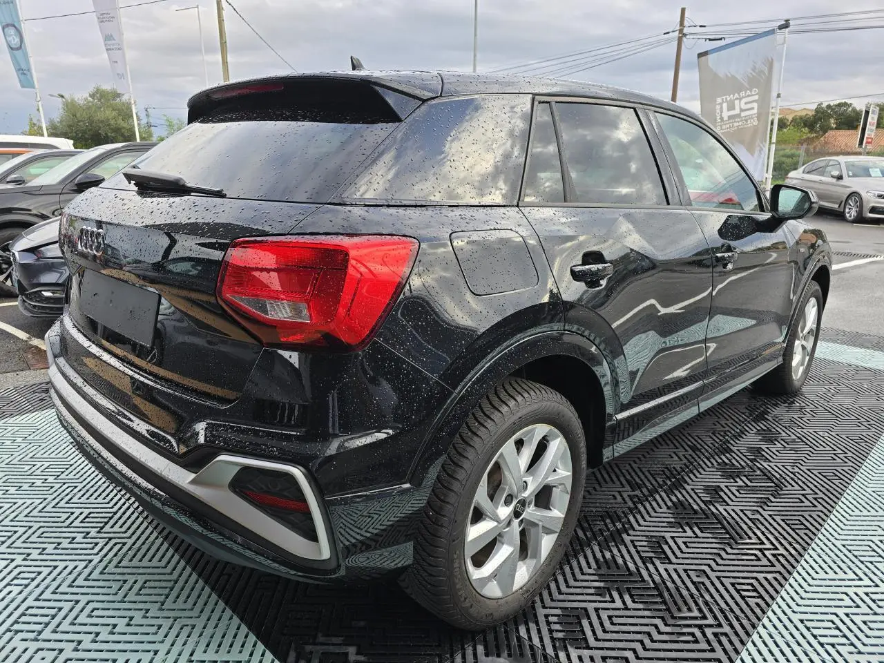 Audi Q2 noir mythic vue 3/4 arrière droit avec jantes aluminium 5 branches doubles et vitres surteintées.