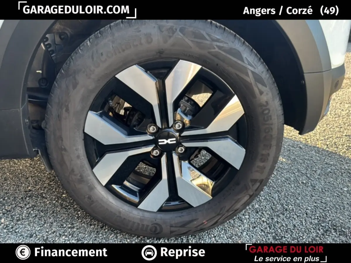 Gros plan sur la roue avant droite d'une Dacia Sandero blanche 2025 avec jante alliage bicolore moderne.