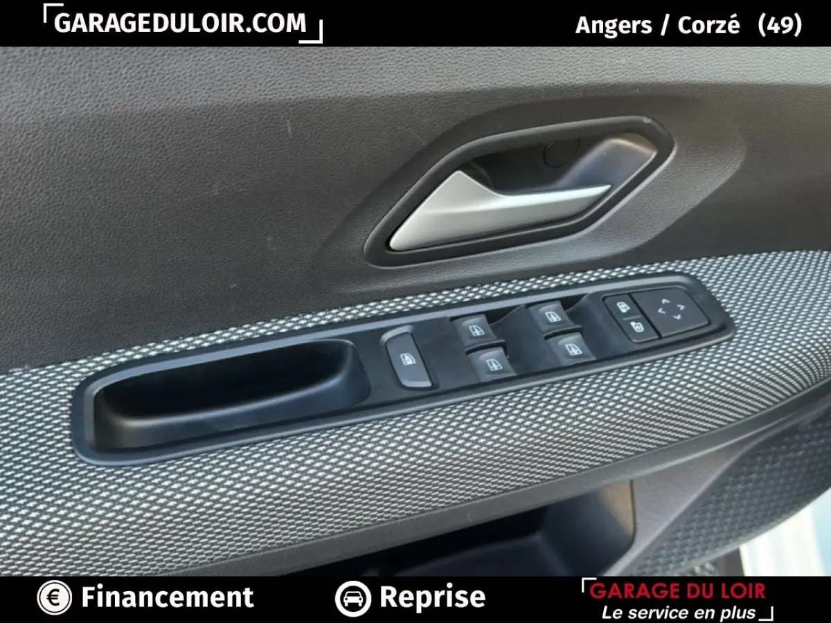 Gros plan sur la commande des vitres électriques et poignée intérieure côté conducteur d’une Dacia Sandero blanche 2025.