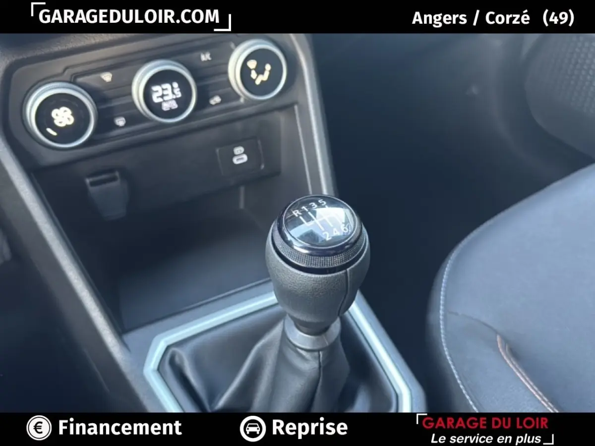 Gros plan sur le levier de vitesses manuel noir de la Dacia Sandero Expression TCe 90 2025 avec console et commandes clim visibles.