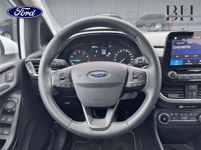 Vue intérieure centrée sur le volant cuir noir d'une Ford Fiesta 2022 avec tableau de bord et écran tactile visible.