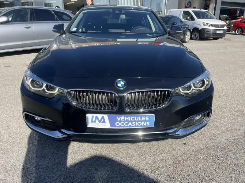 Vue avant d'une BMW Série 4 Gran Coupé 418 da noir métal de 2018 avec calandre double haricot et phares LED allumés.