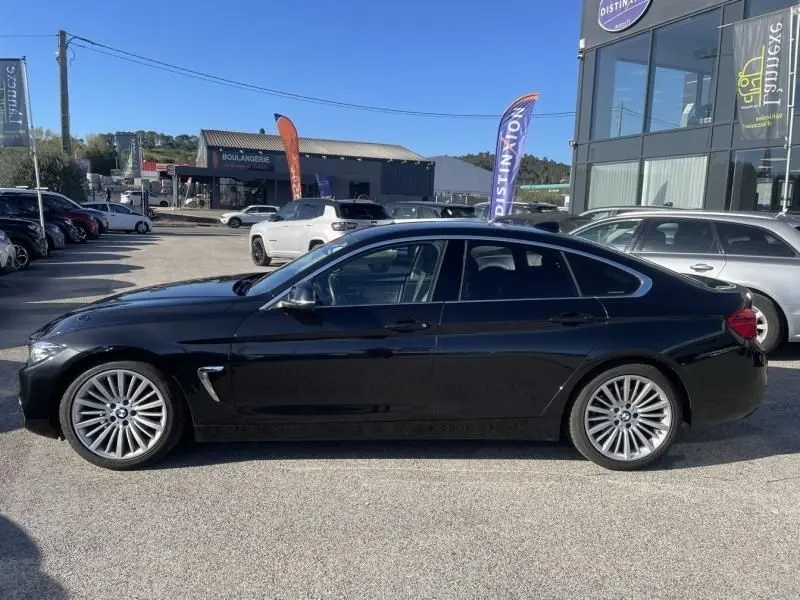 Profil côté gauche d'une BMW Série 4 Gran Coupé 418 da noir métal, avec jantes multi-branches et lignes élégantes.