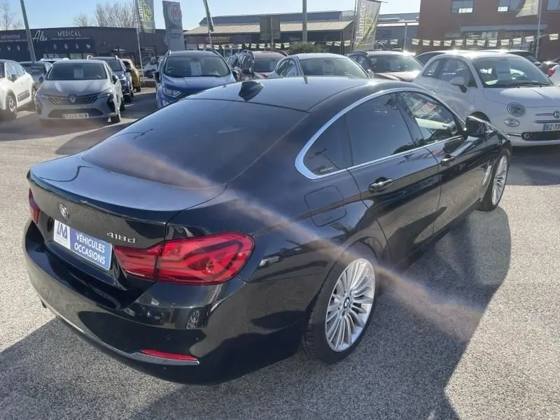 BMW Série 4 Gran Coupé 418d noir métal vue 3/4 arrière droit, avec feux arrière rouges et jantes alliage.