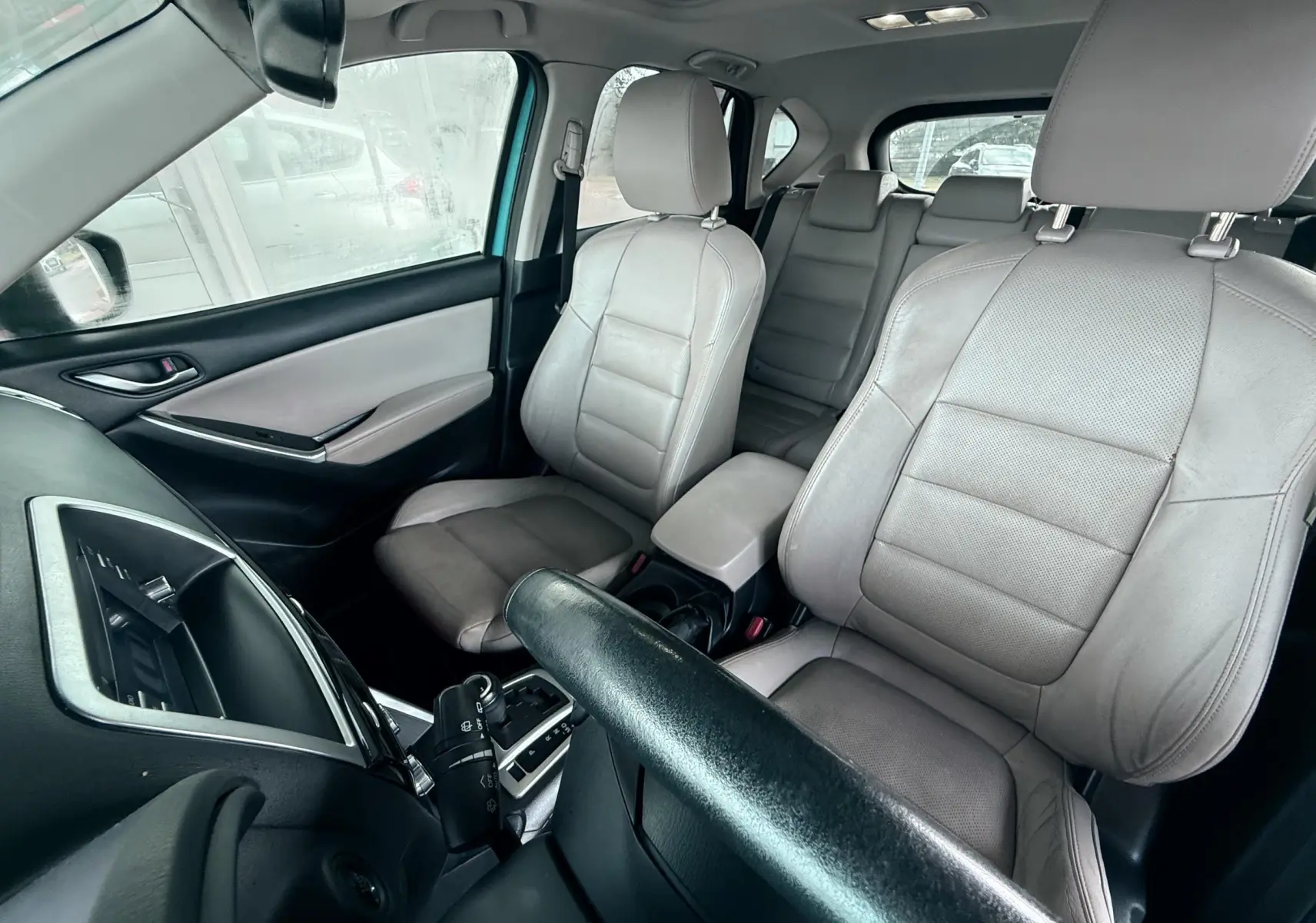 Vue intérieure avant du Mazda CX-5 2013 bleu, sièges en cuir gris clair et console centrale avec boîte automatique visible.