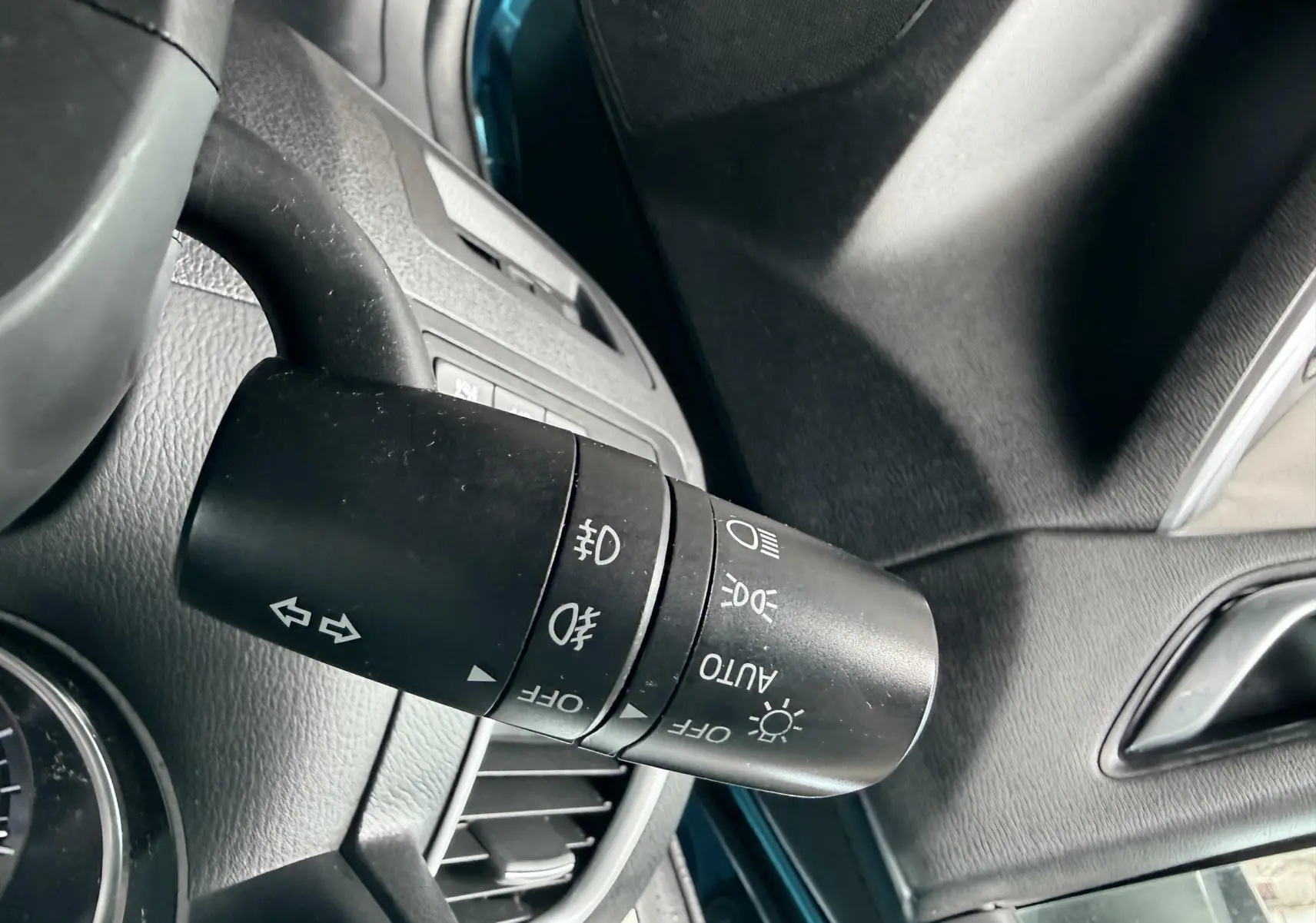 Gros plan sur la commande des phares et clignotants à gauche du volant dans un Mazda CX-5 bleu 2013.