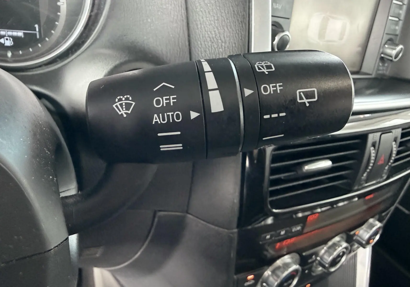 Gros plan sur la commande d’essuie-glace à gauche du volant dans l’habitacle noir du Mazda CX-5 bleu de 2013.