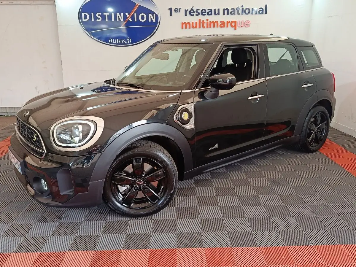 Vue 3/4 avant droite d'un MINI Countryman Cooper SE noir avec jantes noires et détails hybrides visibles sur l'aile.