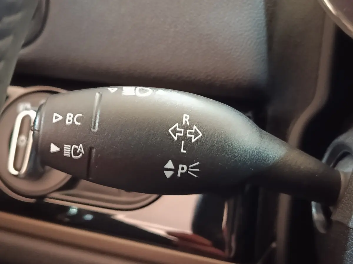Gros plan sur la commande de clignotants noire du MINI COUNTRYMAN Cooper SE 2023, avec symboles blancs visibles.