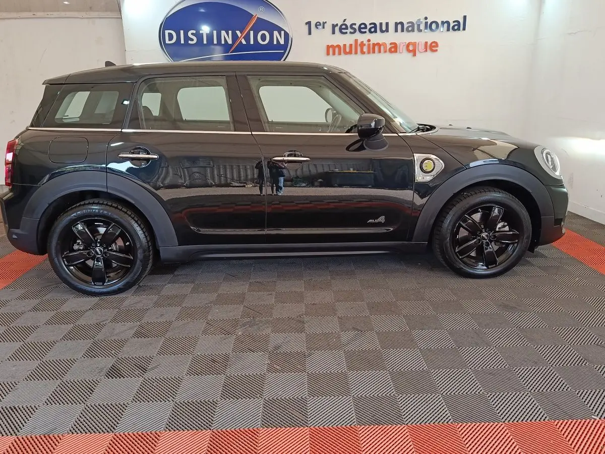 Vue de profil côté gauche d'un MINI Countryman Cooper SE noir avec jantes noires brillantes et logo ALL4 visible.