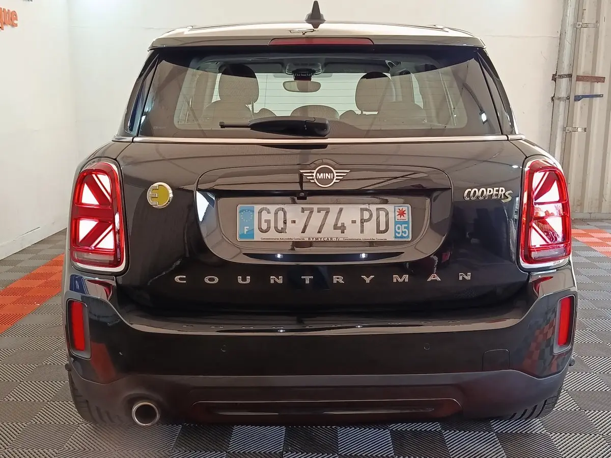 Vue arrière d'une MINI Countryman Cooper S noire avec feux LED et logo hybride jaune visible à gauche.
